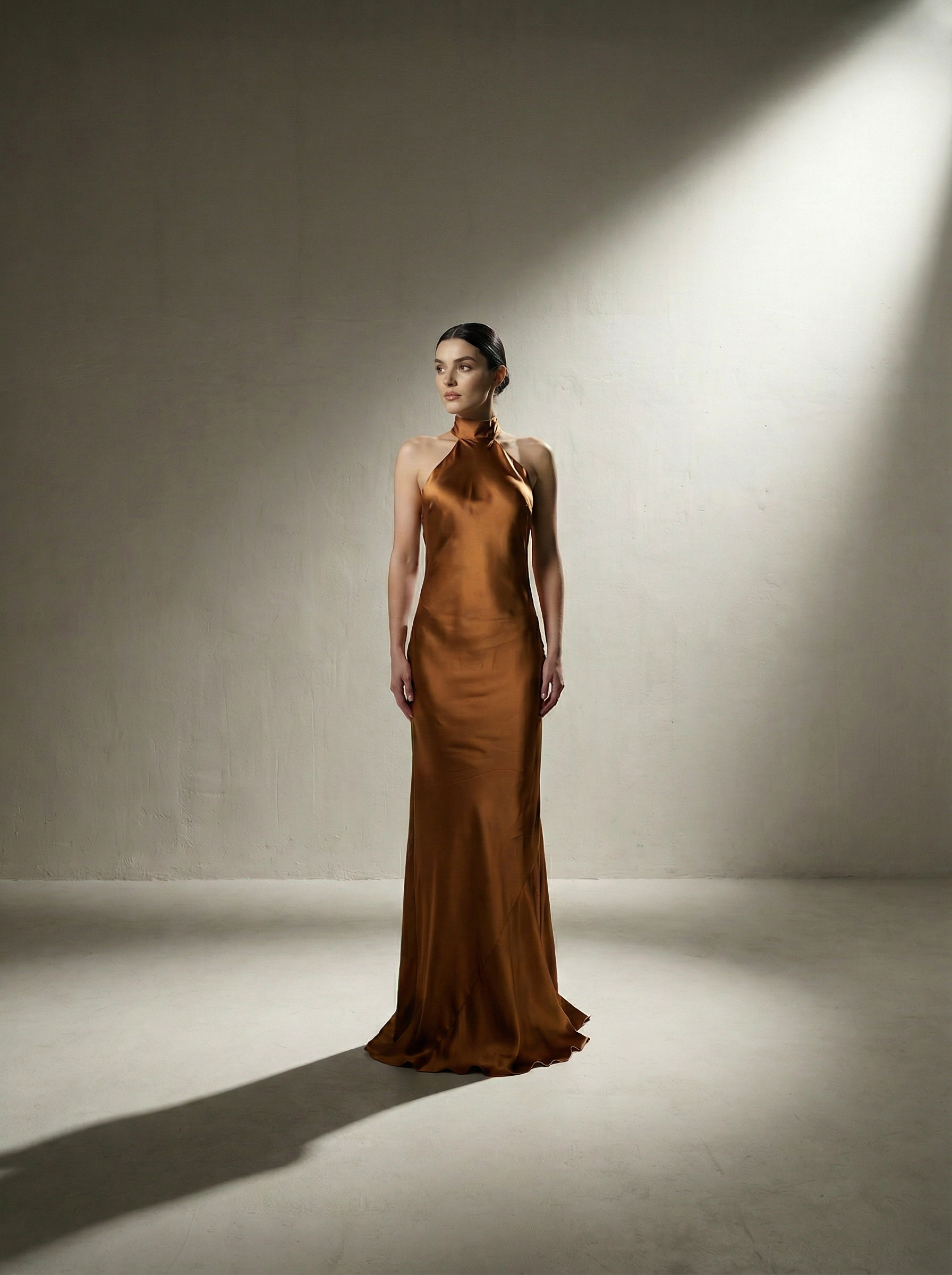 Woman wearing a copper evening gown in a studio setting with spotlight effect