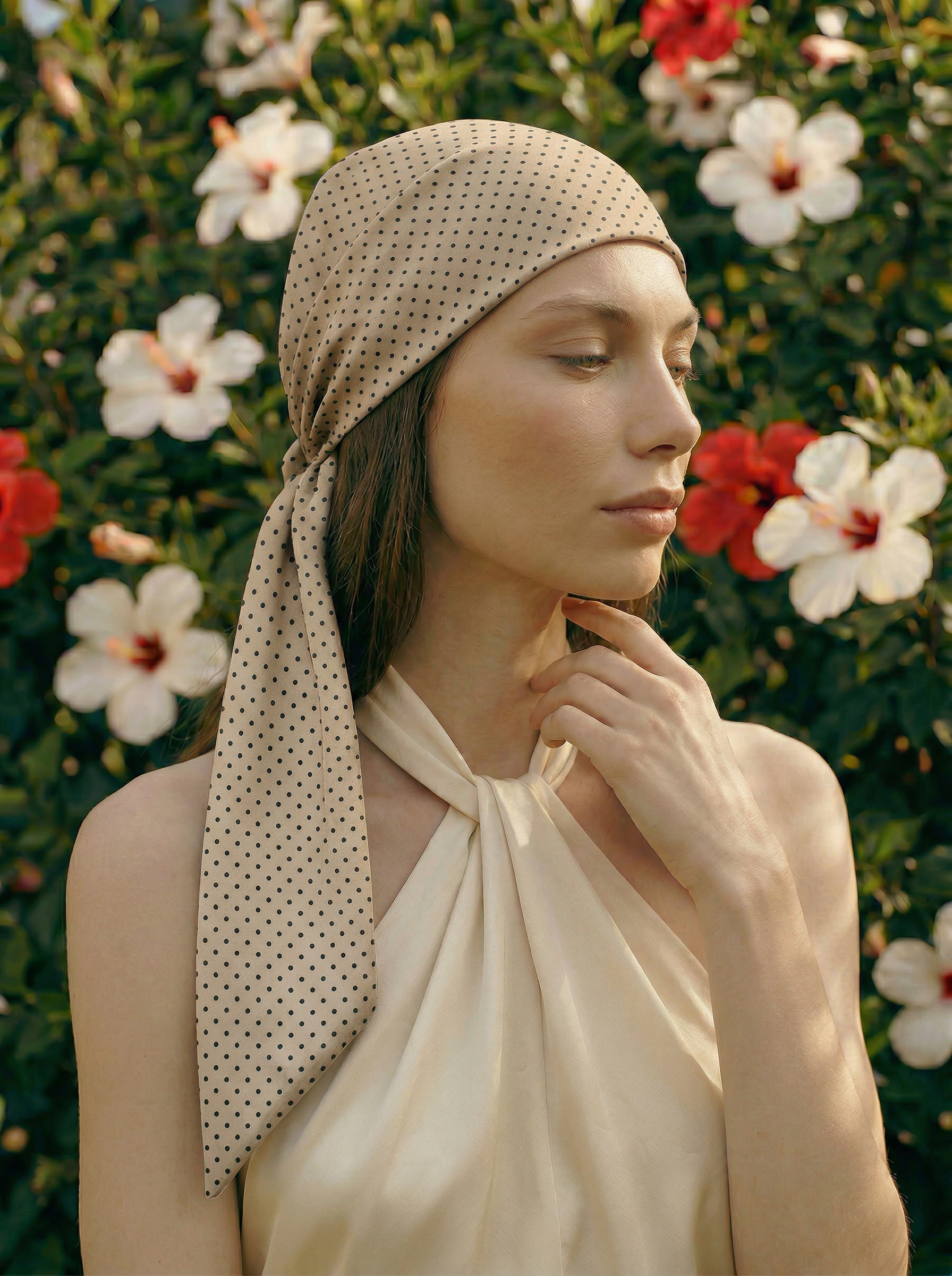 Woman wearing a beige polka dot headscarf with a floral background