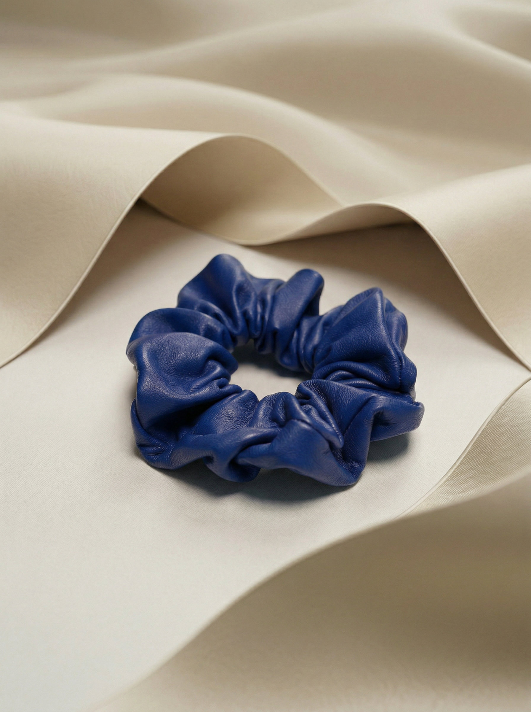 cobalt leather scrunchie next to beige silk fabric