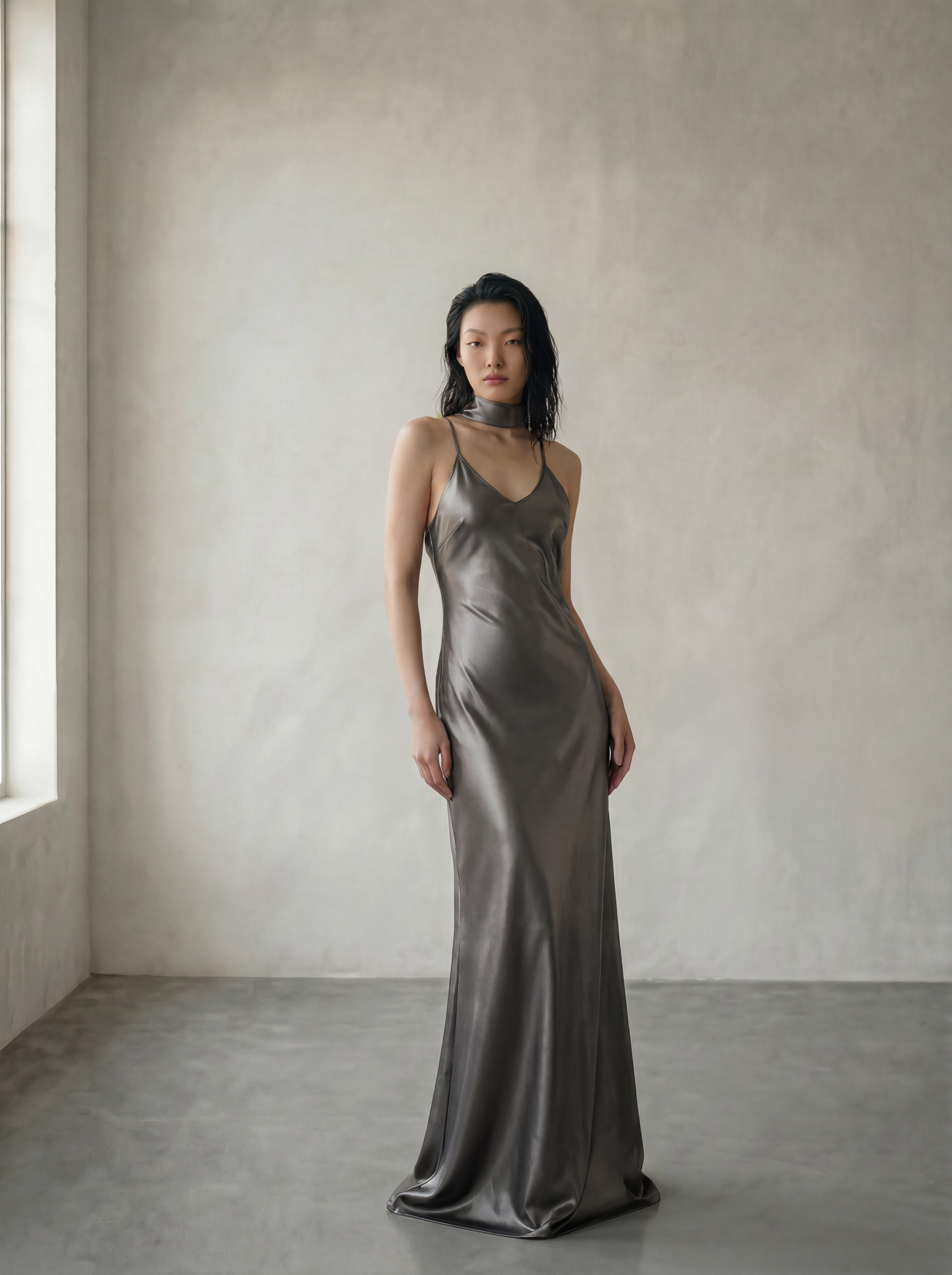 Woman wearing a metallic silver dress against a plain wall.