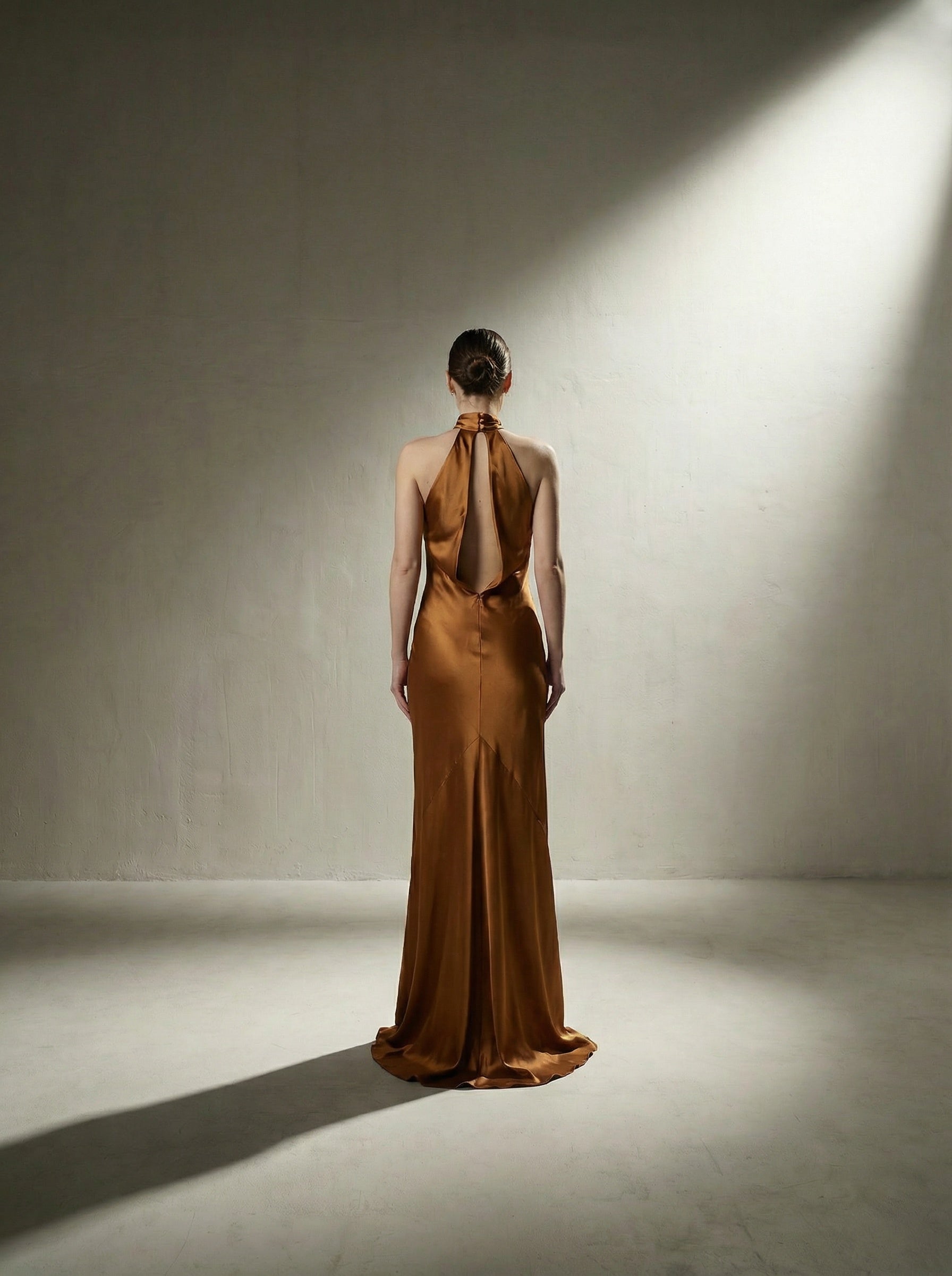 Woman wearing a brown copper evening gown in a studio setting with dramatic lighting.