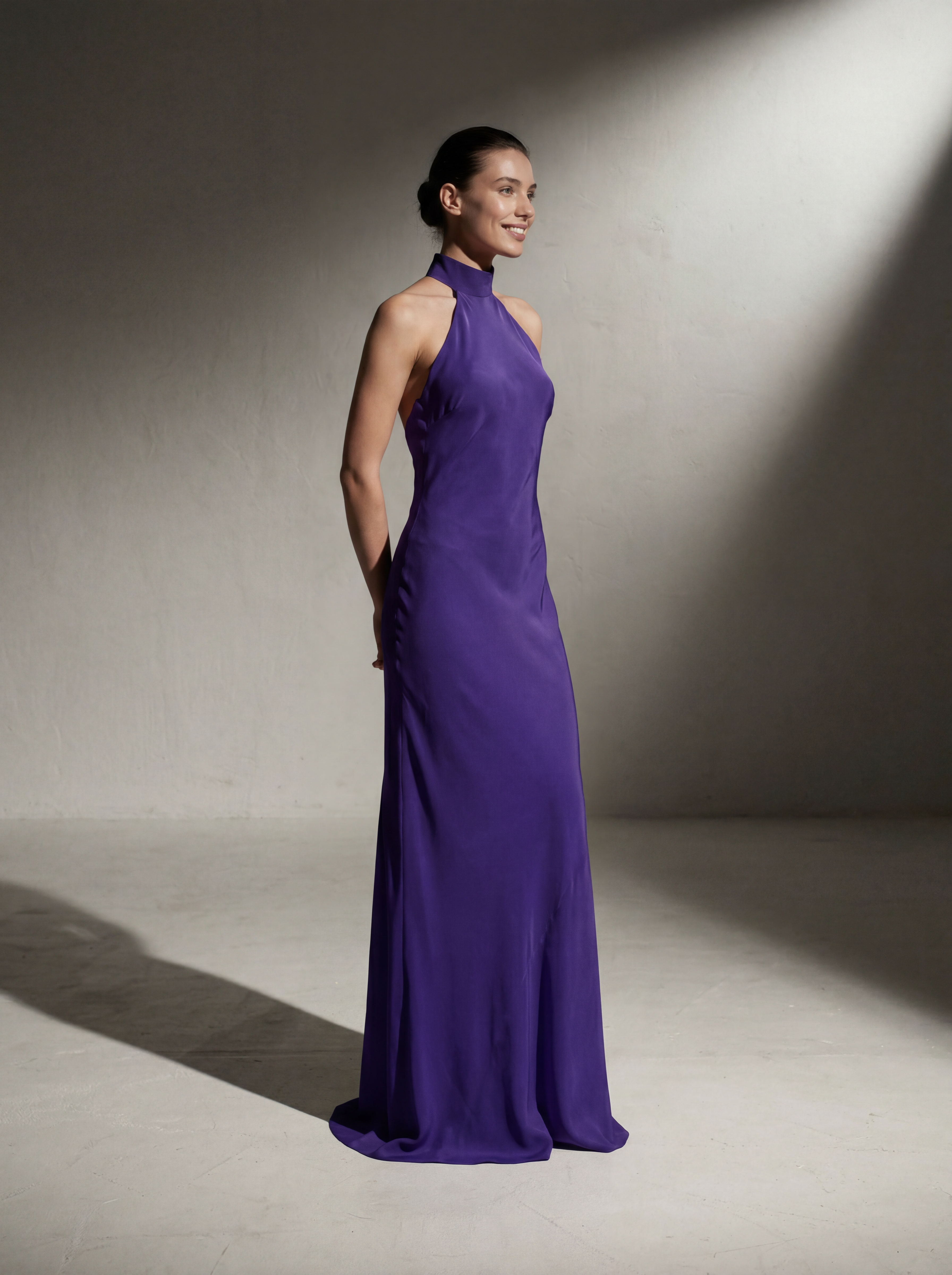 Woman wearing a long purple dress against a neutral background