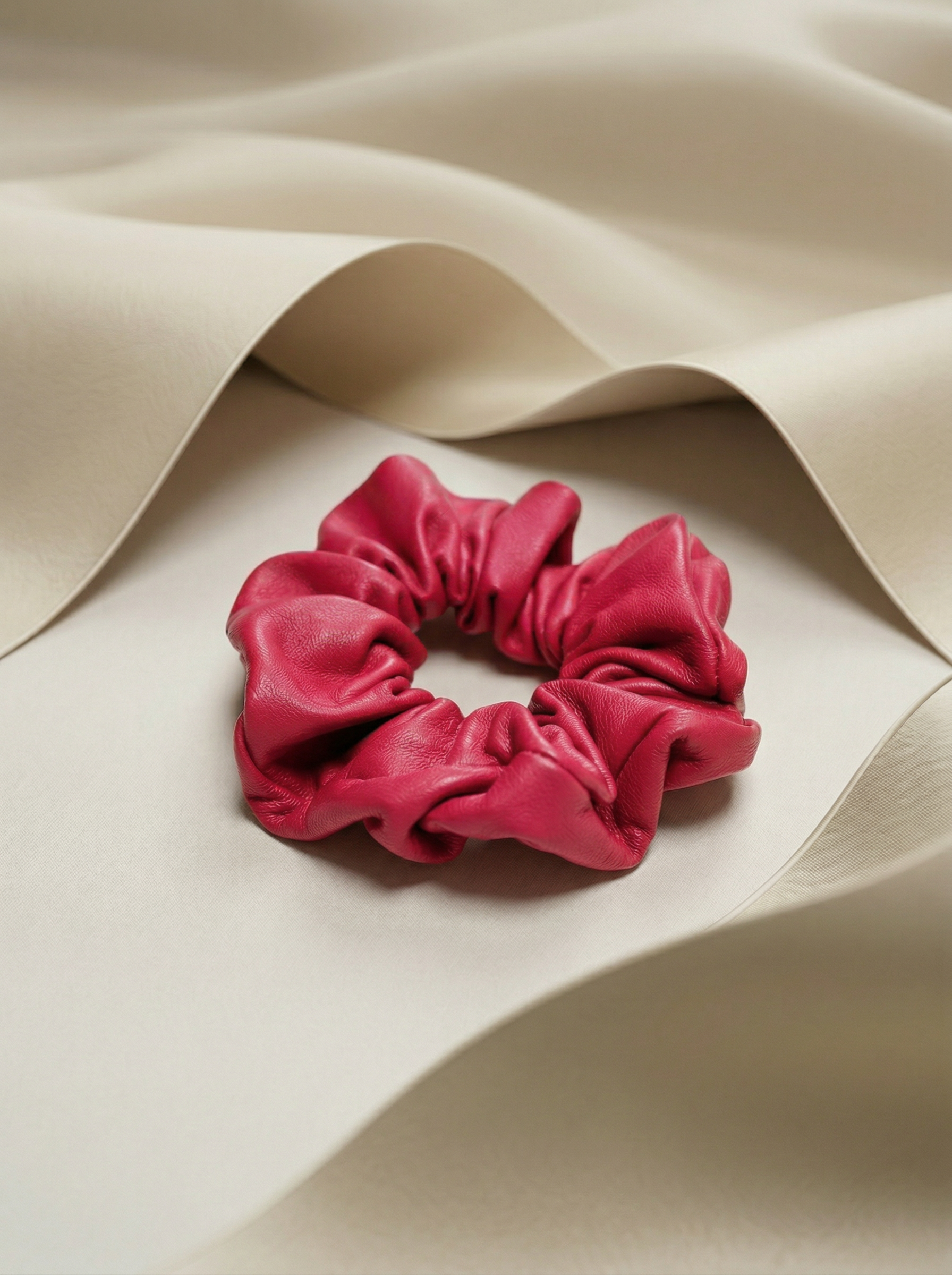 Pink leather scrunchie next to beige silk fabric