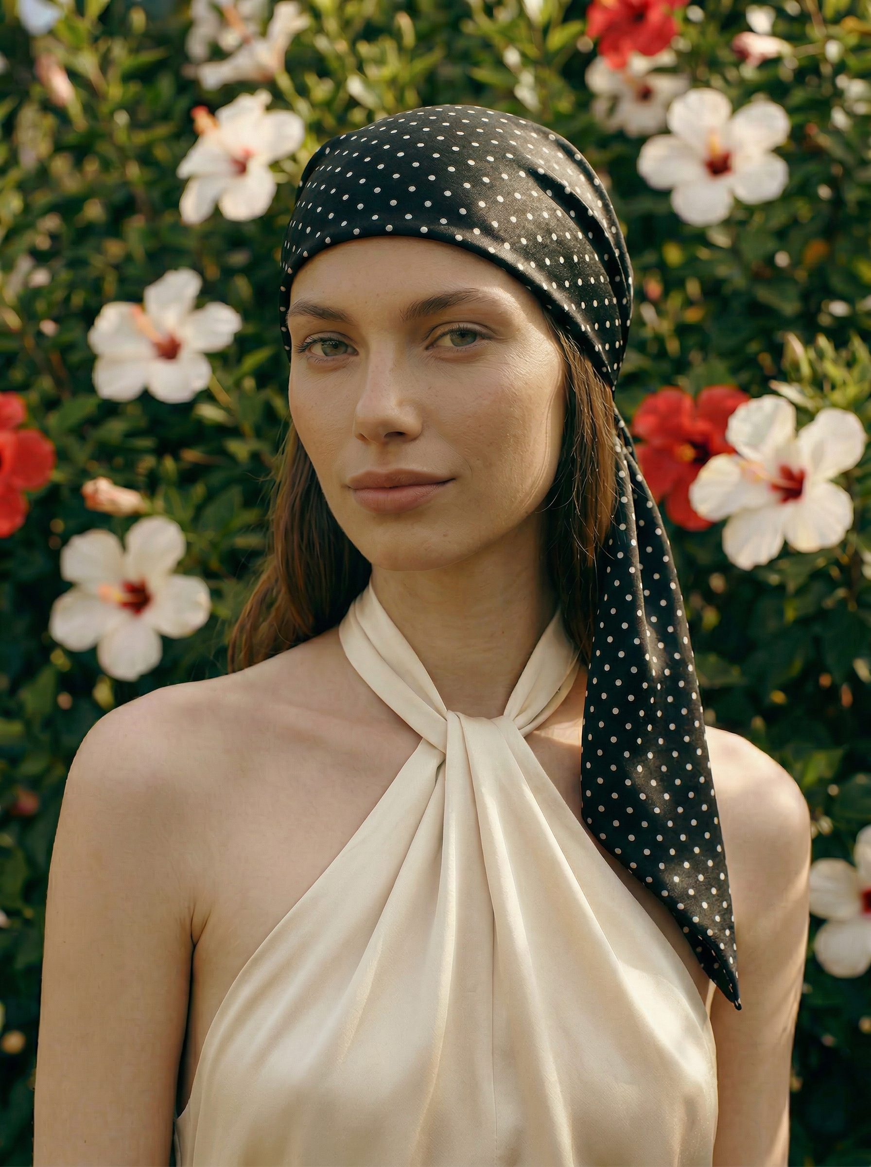 Woman wearing a black polka dot headscarf with a floral background