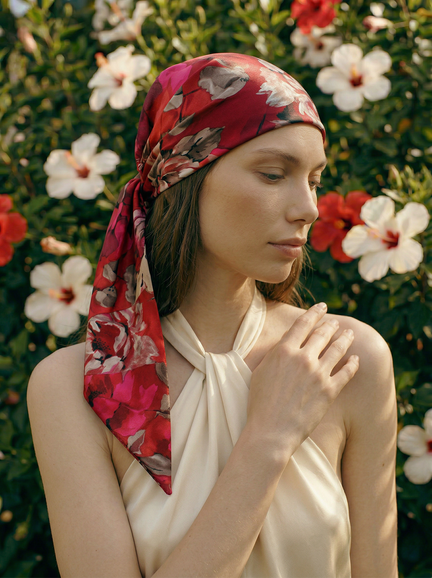 Woman wearing a red floral headscarf with a garden background