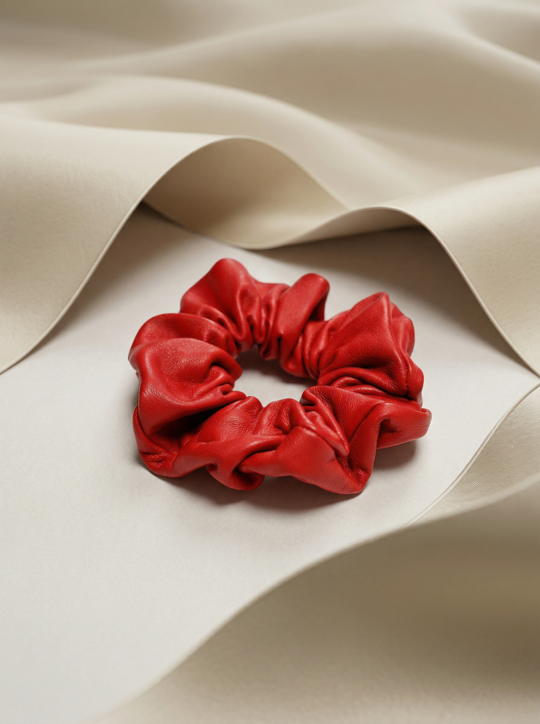 Red leather scrunchie next to beige silk fabric