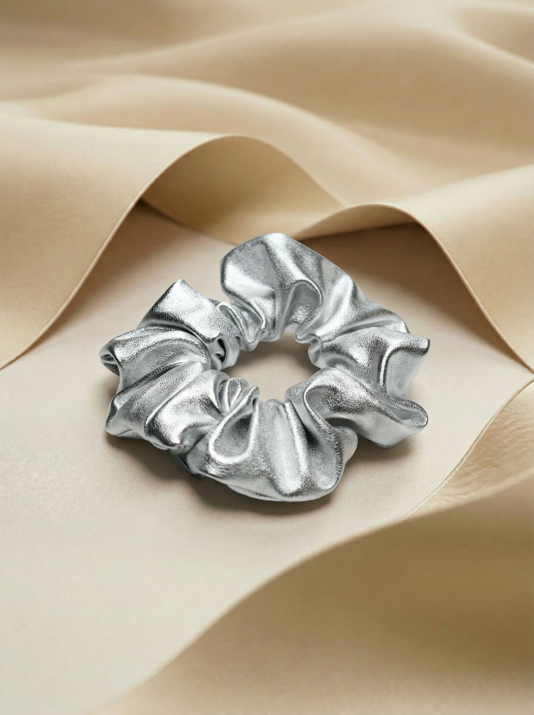 Silver leather scrunchie next to beige silk fabric