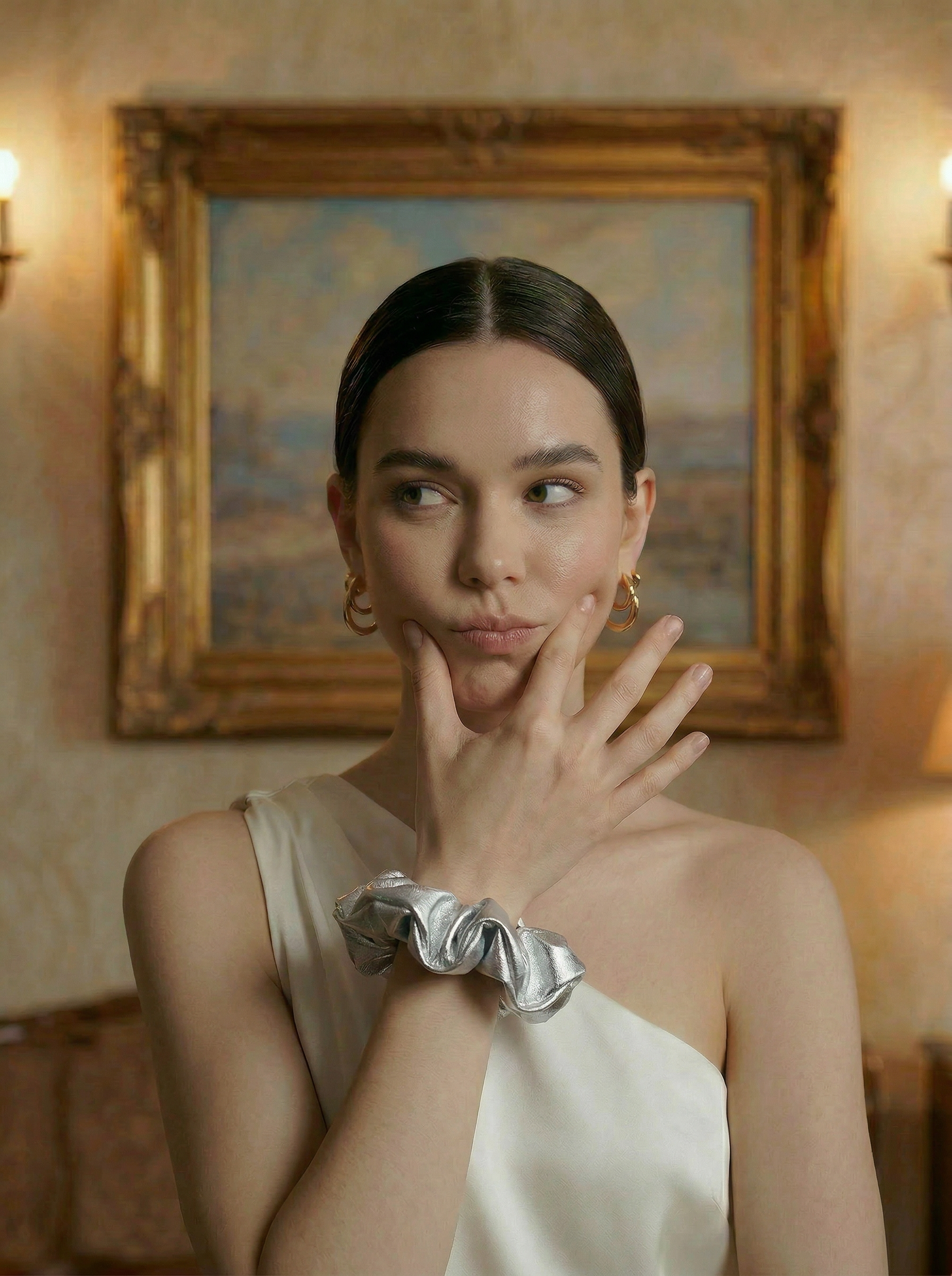 Woman wearing a silver scrunchie in an elegant room with a painting in the background