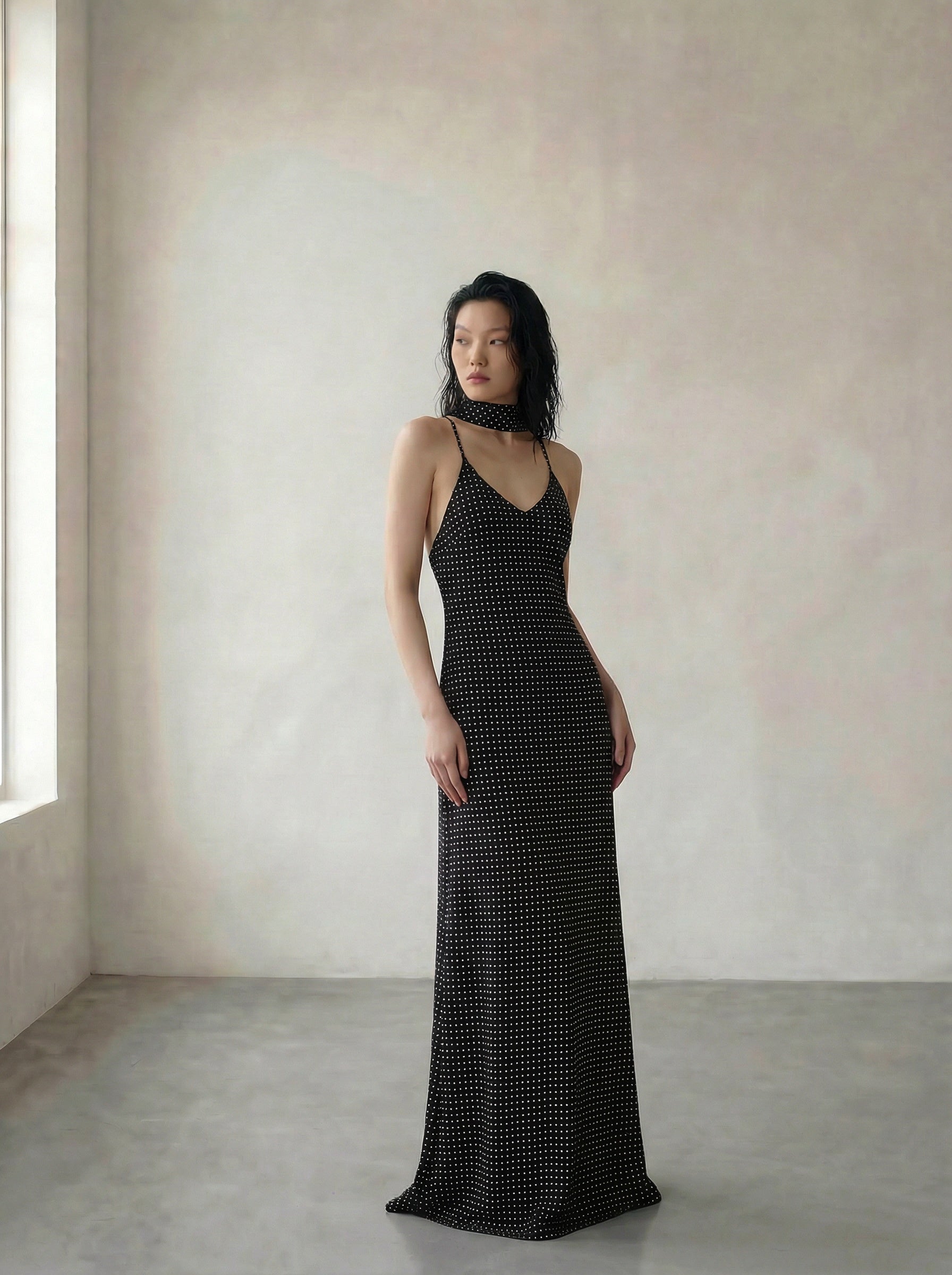 Woman wearing a black polka dot dress in a minimalistic setting