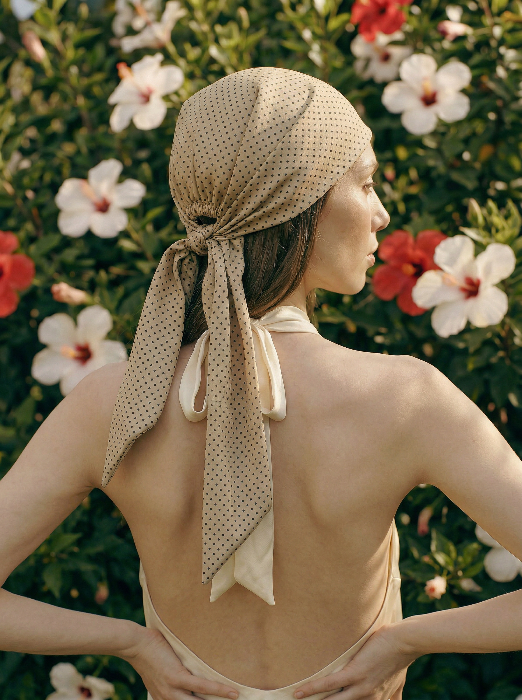 Woman wearing a beige polka dot headscarf with a floral background