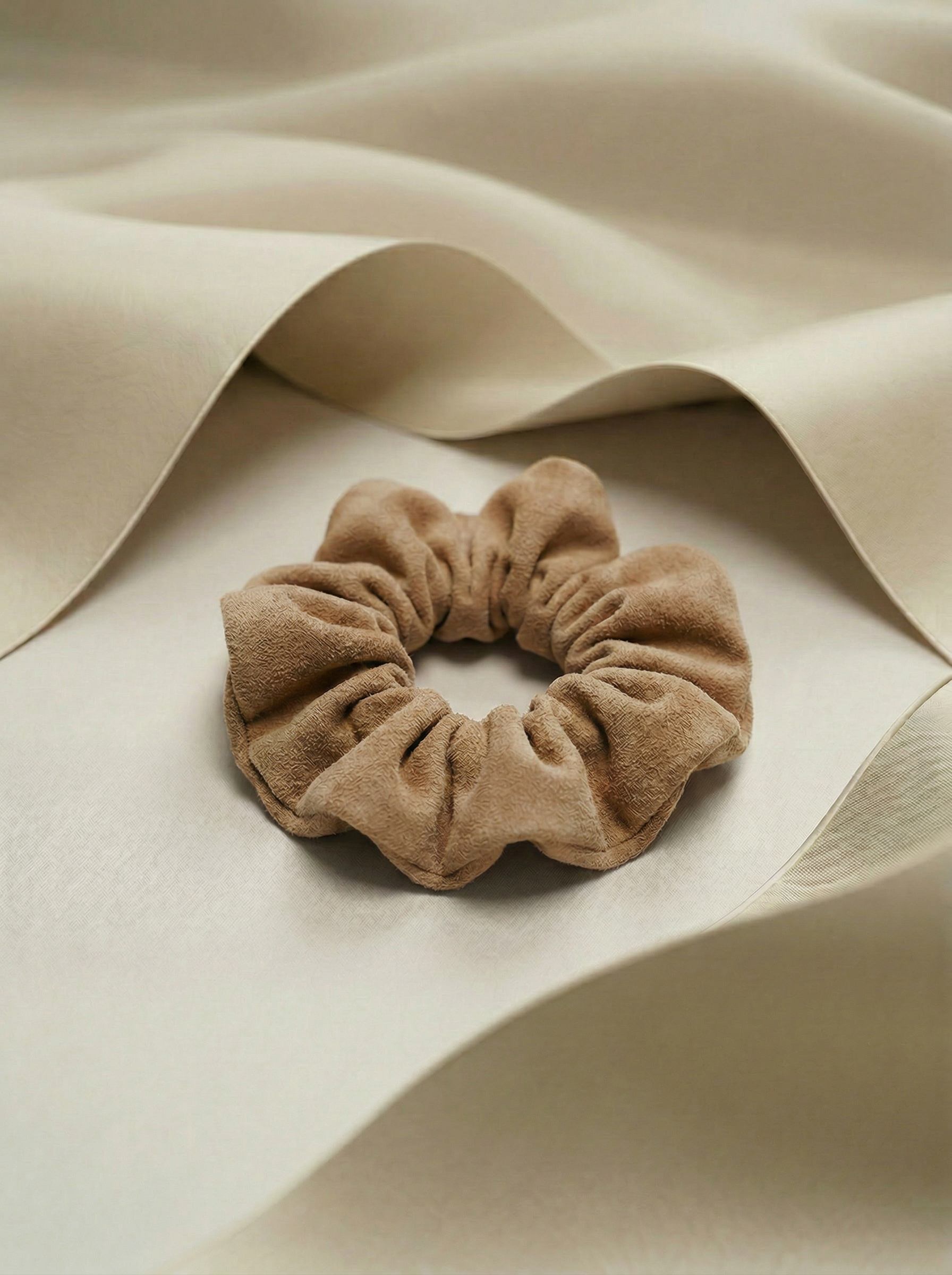 tan color scrunchie on a beige fabric background